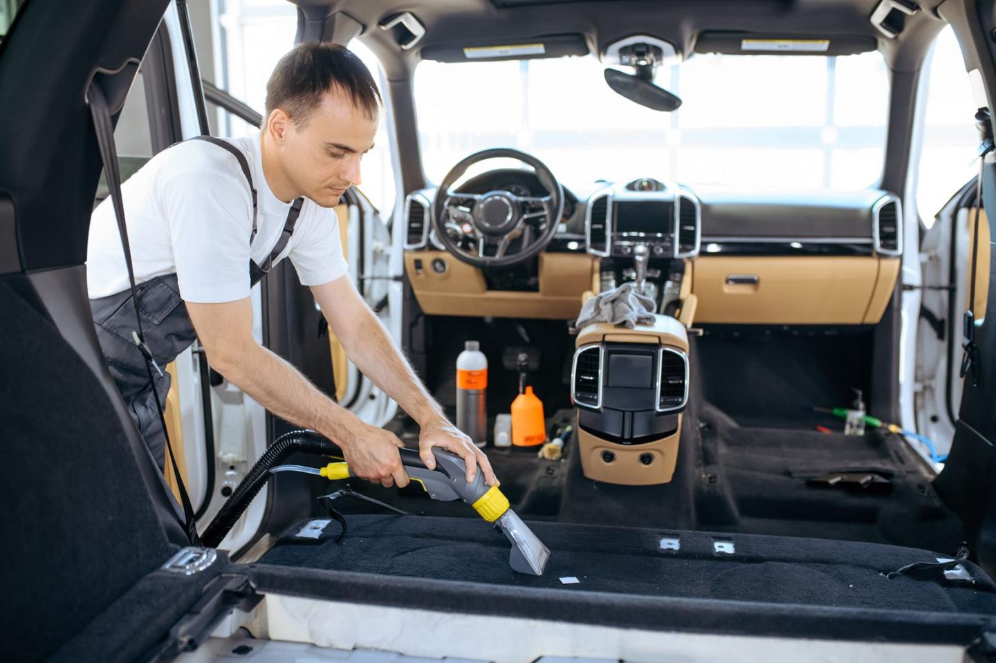 mężczyzna sprząta we wnętrzu samochodu - detailing wnętrza lubin